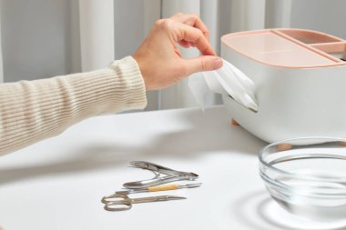 Kadın eli, el hijyeni için beyaz bir dokuyu temizleyiciden çıkarıyor.