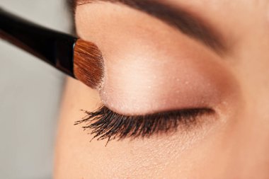 Makyajlı göz farı süren bir kadın. Bir fırçayla, yakın çekim.