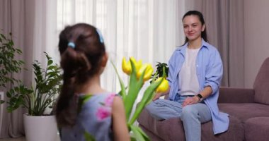 Sevimli küçük kız annesine bir buket sarı lale verip sıkıca sarılıyor. Anneler Günü, Doğum günü ya da Uluslararası Kadınlar Günü 8 Mart konsepti.