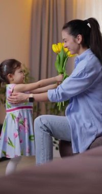 Sevimli küçük kız annesine bir buket sarı lale verip sıkıca sarılıyor. Anneler Günü, Doğum günü ya da Uluslararası Kadınlar Günü 8 Mart konsepti.