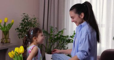 Sevimli küçük kız annesine bir buket sarı lale verip sıkıca sarılıyor.