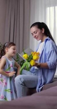 Sevimli küçük kız annesine bir buket sarı lale verip sıkıca sarılıyor.