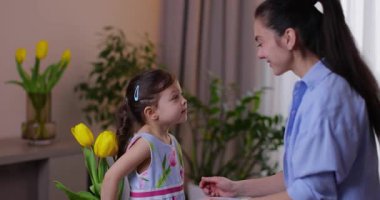 Sevimli küçük kız annesine bir buket sarı lale verip sıkıca sarılıyor.