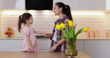 Sevimli küçük kız ve annesi modern bir mutfakta lezzetli kurabiyeler yiyorlar.