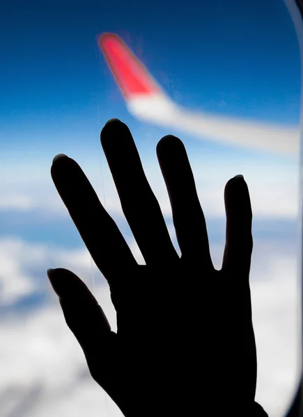 Frauenhand an einem Flugzeugfenster — Stockfoto