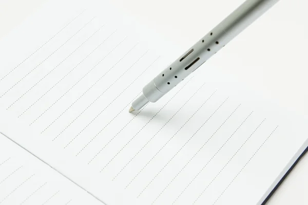 Długopis metalowy stoi na kartce notatnik — Zdjęcie stockowe