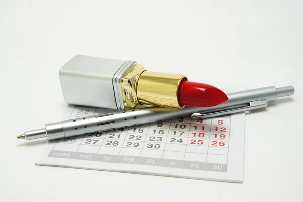 Lipstick and pen on calendar — Stock Photo, Image