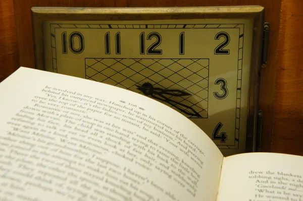 Buch aufschlagen über Hintergrund alte Uhr. — Stockfoto