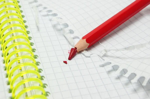 Kırmızı kalem defter üzerinde kırık.