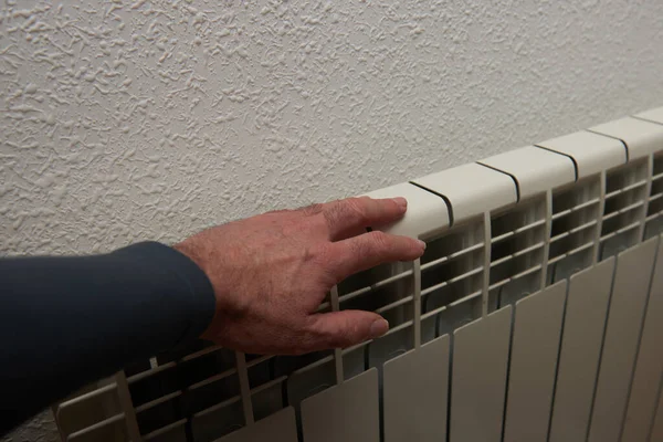 A man\'s hand checking the temperature of a radiator