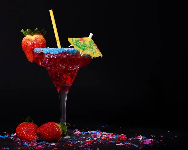 A delicious martini cocktail with ice and strawberries on a black background