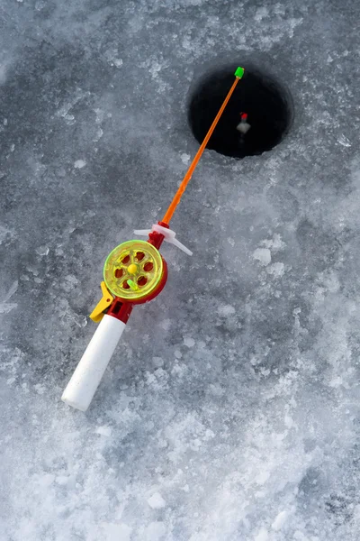 La canna per pesca invernale si trova vicino a un buco — Foto Stock