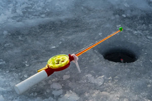 La canna per pesca invernale si trova vicino a un buco — Foto Stock