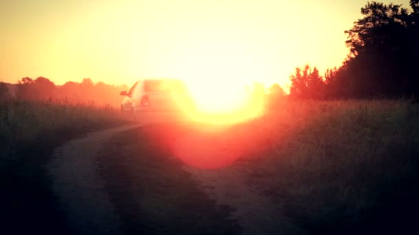 O carro se afasta para os raios de sol nascente — Vídeo de Stock