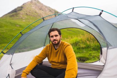 Genç ve çekici bir adam çadırına kurulmuş İskoçya 'da doğanın tadını çıkarırken tek başına kamp yapıyor.