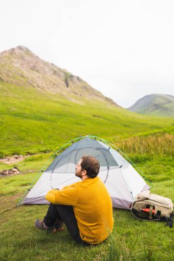 Genç ve çekici bir adam çadırına kurulmuş İskoçya 'da doğanın tadını çıkarırken tek başına kamp yapıyor.