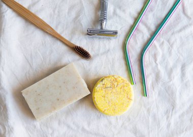 Sıfır atık ürün, başlığı kapat. Bambu diş fırçası, sağlam şampuan, metal jilet, metal kamışlar ve sağlam el sabunu. Beyaz arka planda sürdürülebilir banyo ürünleri.