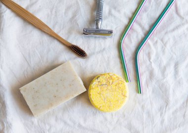 Sıfır atık ürün, başlığı kapat. Bambu diş fırçası, sağlam şampuan, metal jilet, metal kamışlar ve sağlam el sabunu. Beyaz arka planda sürdürülebilir banyo ürünleri.