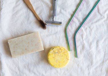 Sıfır atık ürün, başlığı kapat. Bambu diş fırçası, sağlam şampuan, metal jilet, metal kamışlar ve sağlam el sabunu. Beyaz arka planda sürdürülebilir banyo ürünleri.