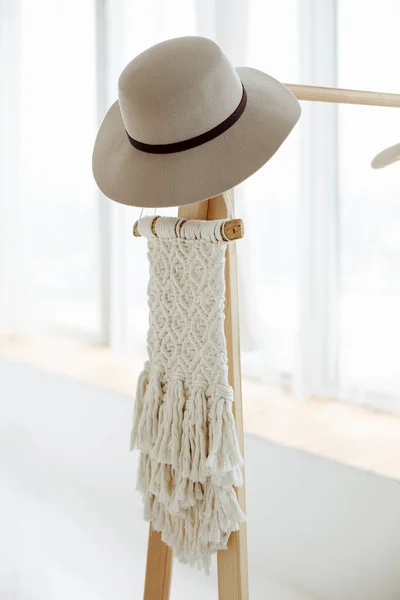 流行の木製の服ハンガーとミニマリストの廊下のインテリアは白い壁に対して立つ ハンガーにスタイリッシュなブラウンの帽子を感じます スペースのコピー ロイヤリティフリーのストック写真