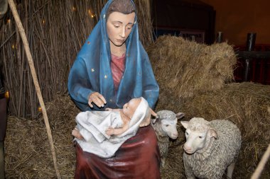İncil 'den bir sahne, heykellerin yardımıyla sahnelenmiş. İsa 'nın. Bir kadın kucağında bir bebek tutuyor. Yakınlarda koyun ve saman var.