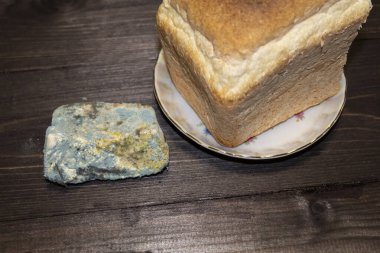 Tabakta yarım somun taze ekmek ve yanında bir dilim küflü ekmek var.. 