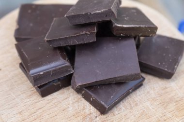 Close-up. Pieces of dark chocolate lie on a cutting board. 