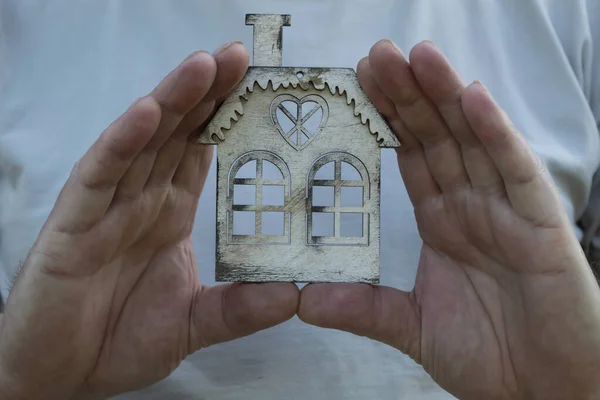A man holds in his hands a model of a house he wants to buy.