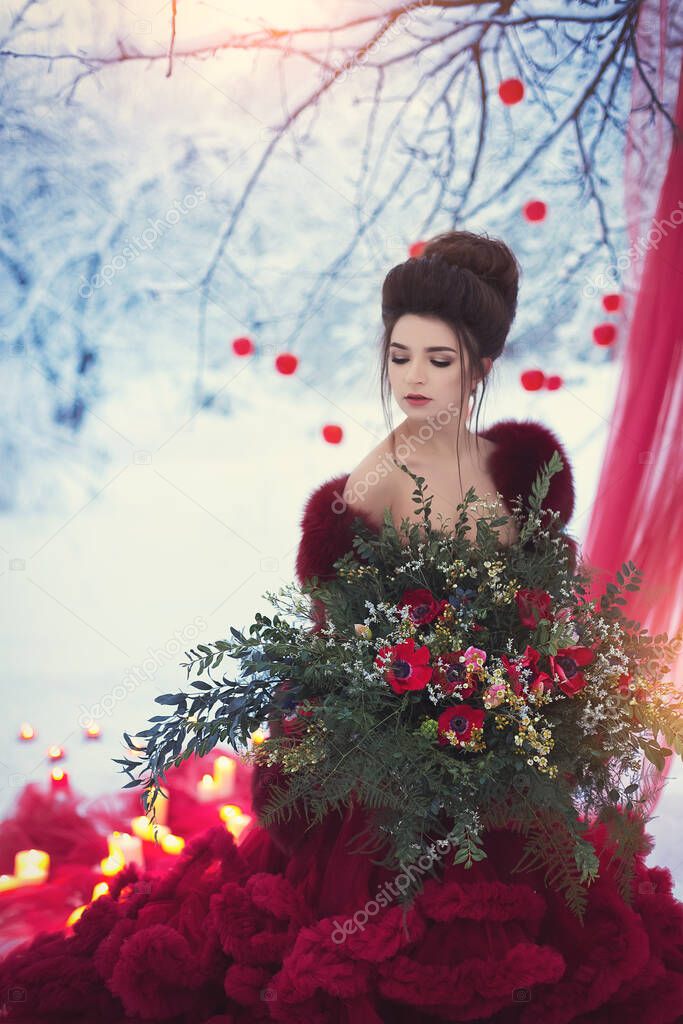 A young girl in a lush Marsala dress on the background of a dark red wedding decor with tulle, apples and candles on the background of a snowy forest. Winter country wedding ceremony.