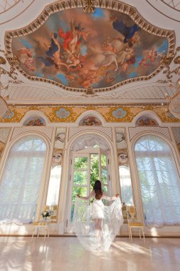 Lüks bir tarihi villanın arka planında beyaz dantelli bir elbise giyen güzel bir genç kız. Romantik güneşli gelin sabahı.