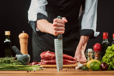 Şefin bıçağını tutan ve et kesmek üzere olan bir adam.
