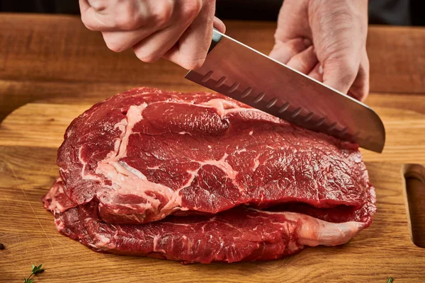 Szef kuchni kroi mięso wołowe nożem Santoku na drewnianej desce do krojenia — Zdjęcie stockowe
