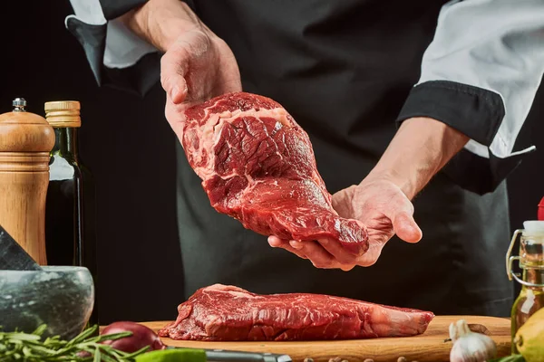 Szef kuchni pokazuje kawałek mięsa. Zioła, czosnek, pieprz, nasiona i oliwa z oliwek — Zdjęcie stockowe