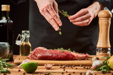 Şef bir parça ete kekik ekliyor. Çiğ biftek çeşnili adam.