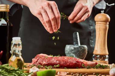 Şef çiğ bifteğin üzerine kekik serper, yakın çekim.
