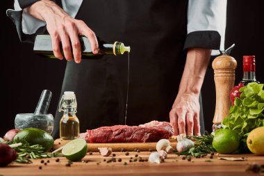 Aşçı çiğ ete zeytinyağı döküyor.