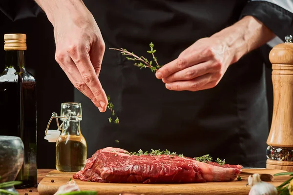 Szef kuchni dodaje świeżego tymianku do kawałka mięsa — Zdjęcie stockowe