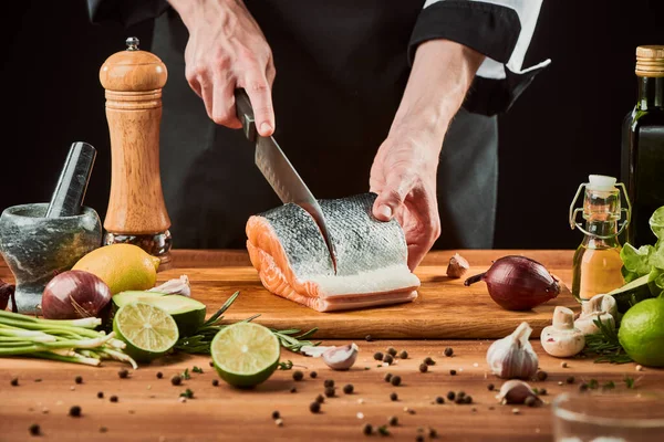 Chef cutting salmon fillet into steaks on a wooden board