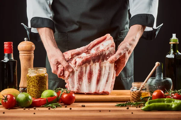 Een man met rauwe ribben. Chef bereidt vlees voor het grillen — Stockfoto