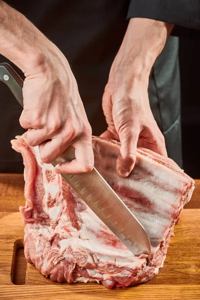 Chef cortando costelas de carne crua com uma faca Santoku afiada — Fotografia de Stock