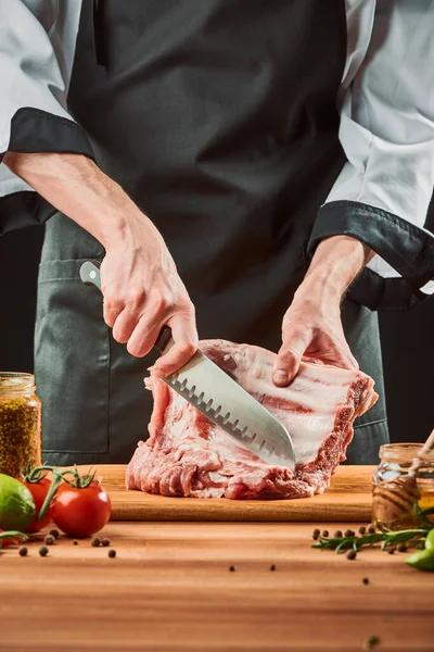 Homem cortando costelas de carne crua, tiro no meio — Fotografia de Stock