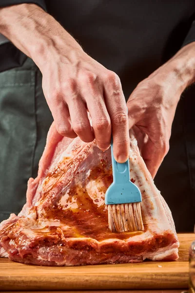 Homem escovando costelas de carne com marinada, tiro de close-up — Fotografia de Stock