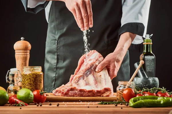 Chef joga uma pitada de sal em costelas de carne — Fotografia de Stock