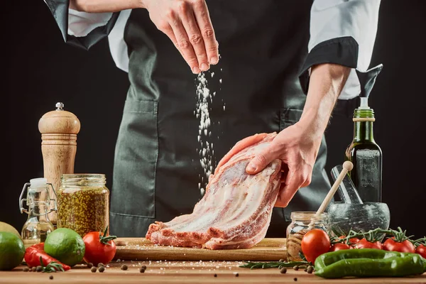 Chef salting raw beef ribs, throwing a big pinch onto the piece of meat — Stock Image Chef salting raw beef ribs, throwing a big pinch onto the piece of meat Stock Picture