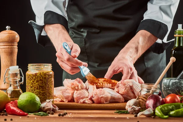 Chef-kok borstelt kippenvleugels met barbecuesaus — Stockfoto