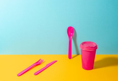 Pembe plastik çatal bıçak takımı ve kağıt kahve fincanı.