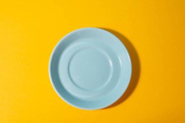 Sarı arka planda mavi çay tabağının üst görüntüsü