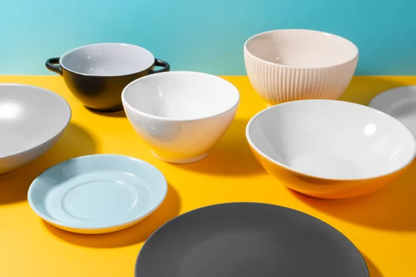Ποικιλία πιάτων και μπολ σε κίτρινο τραπέζι — Φωτογραφία Αρχείου