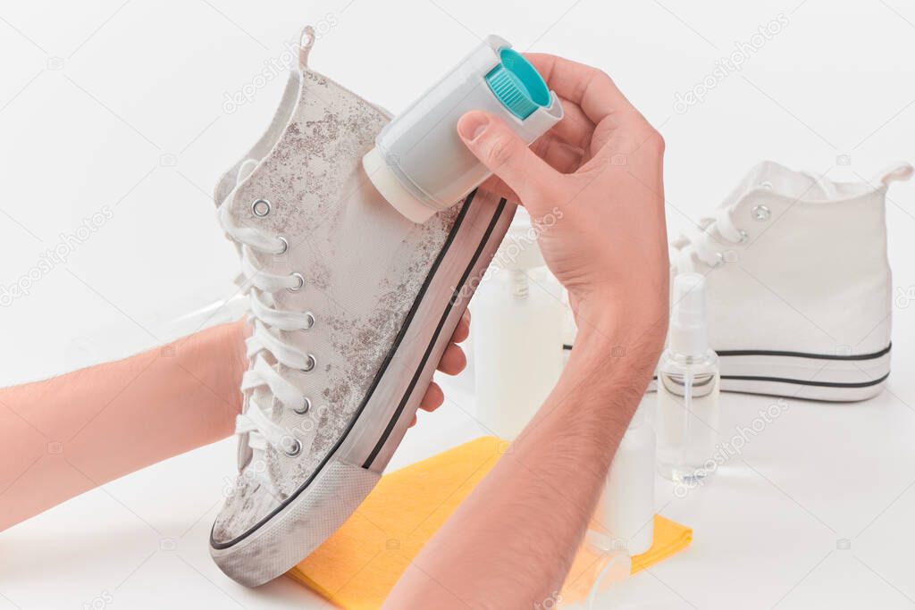 Man removing dirt from a canvas sneaker with a powerful detergent