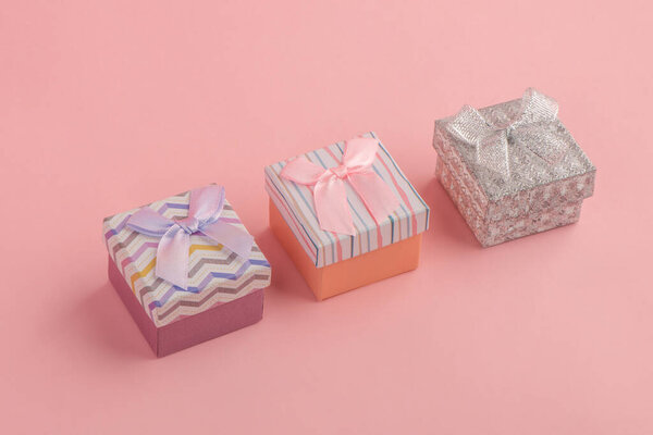 Three tiny gift boxes on pink background